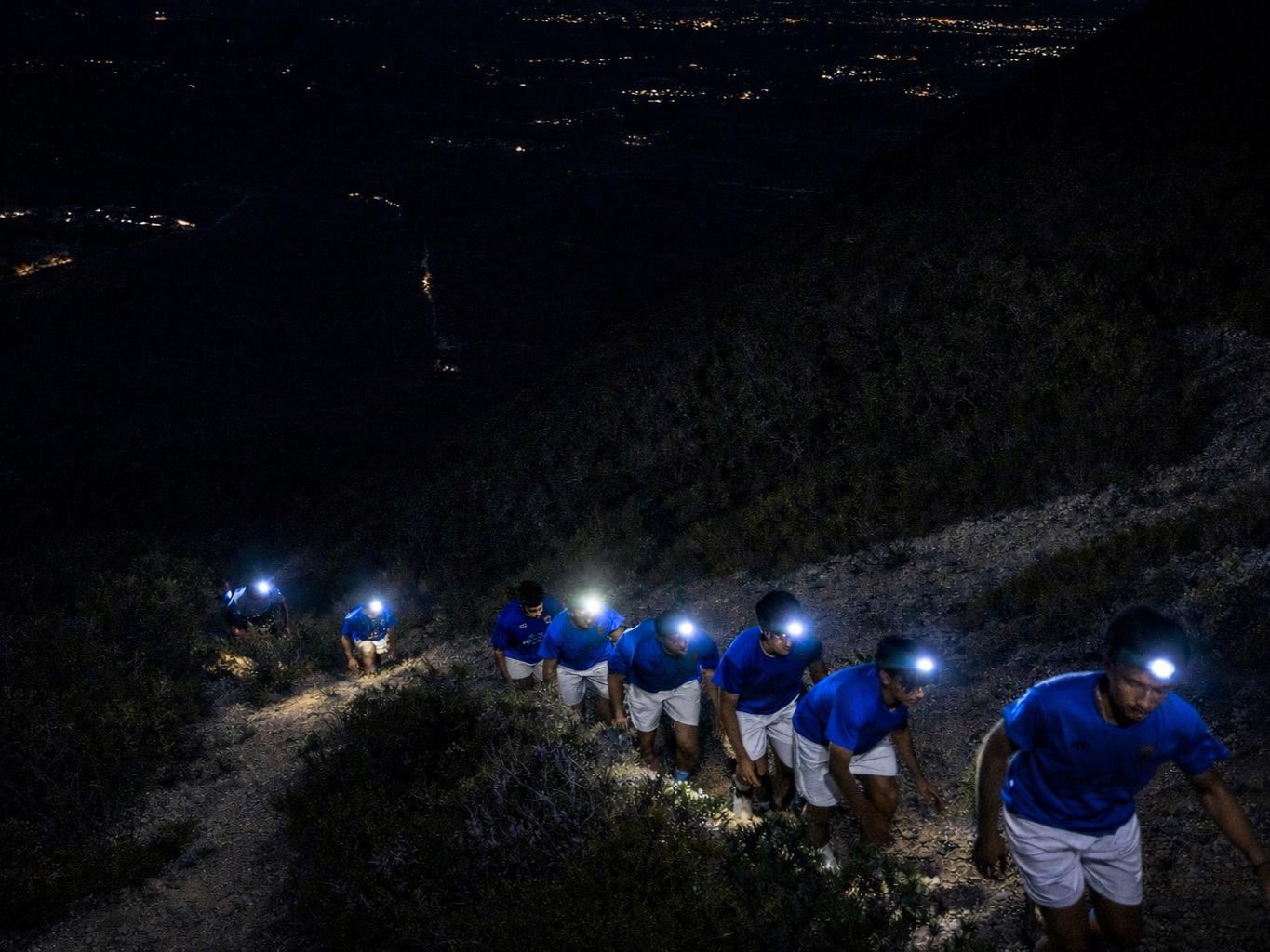 equipa  de clube desportivo a fazer caminhada noturna com lanternas frontais na cabeça